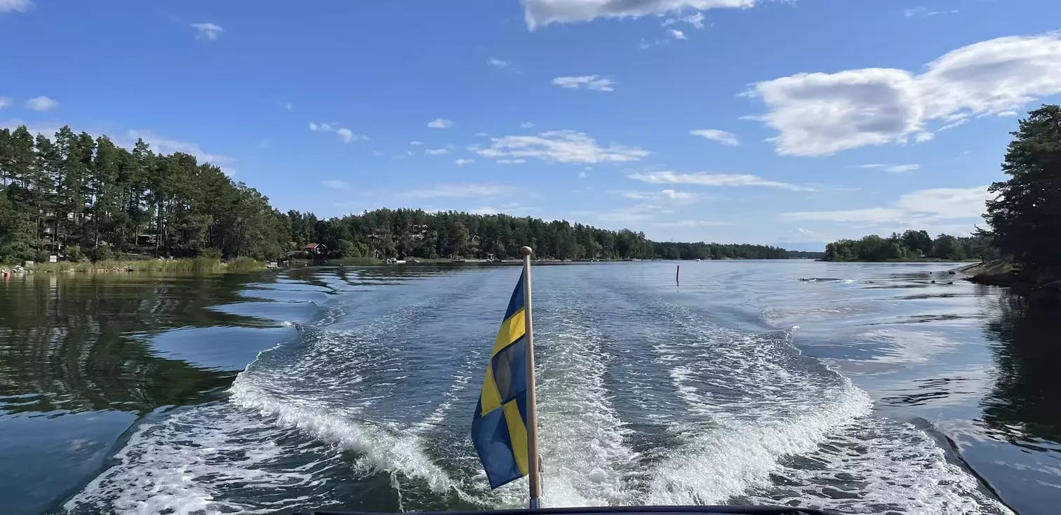 Båt på sjön med svenska flaggan i aktern